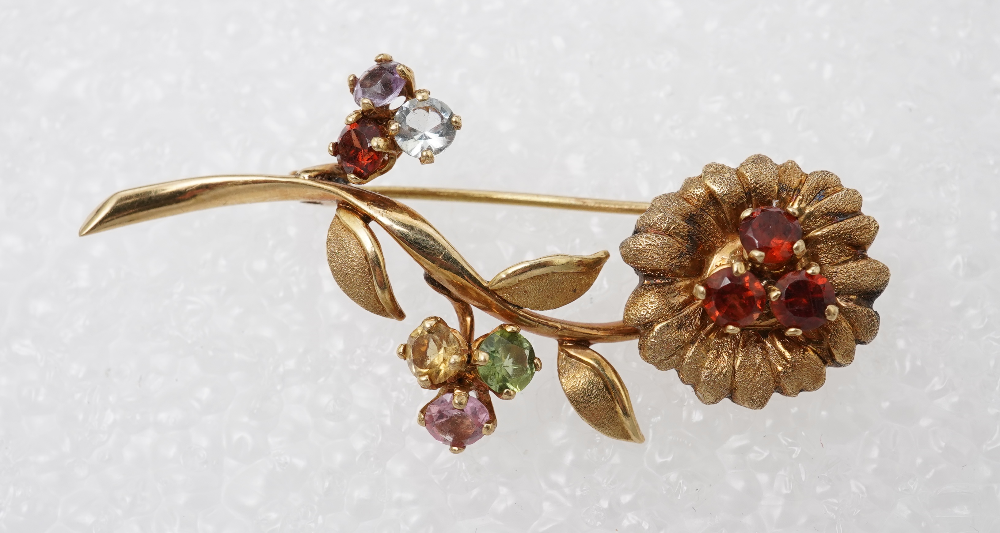 Two brooches and a ring, mid 20th century, comprising: a brooch of floral design, set with circular-cut synthetic gemstones, length 3.7cm, Austrian assay marks for gold, gross weight approximately 6.5 grams; a brooch des